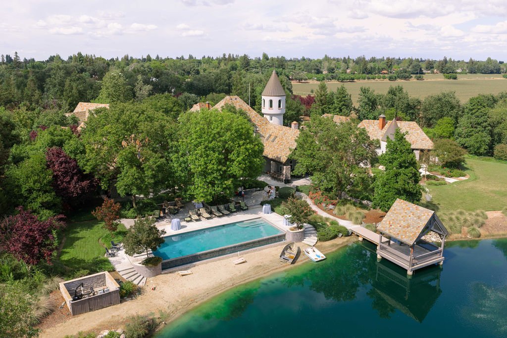 Aerial view of the estate: the castle, infinity pool, sandy beach and lake gazebo
