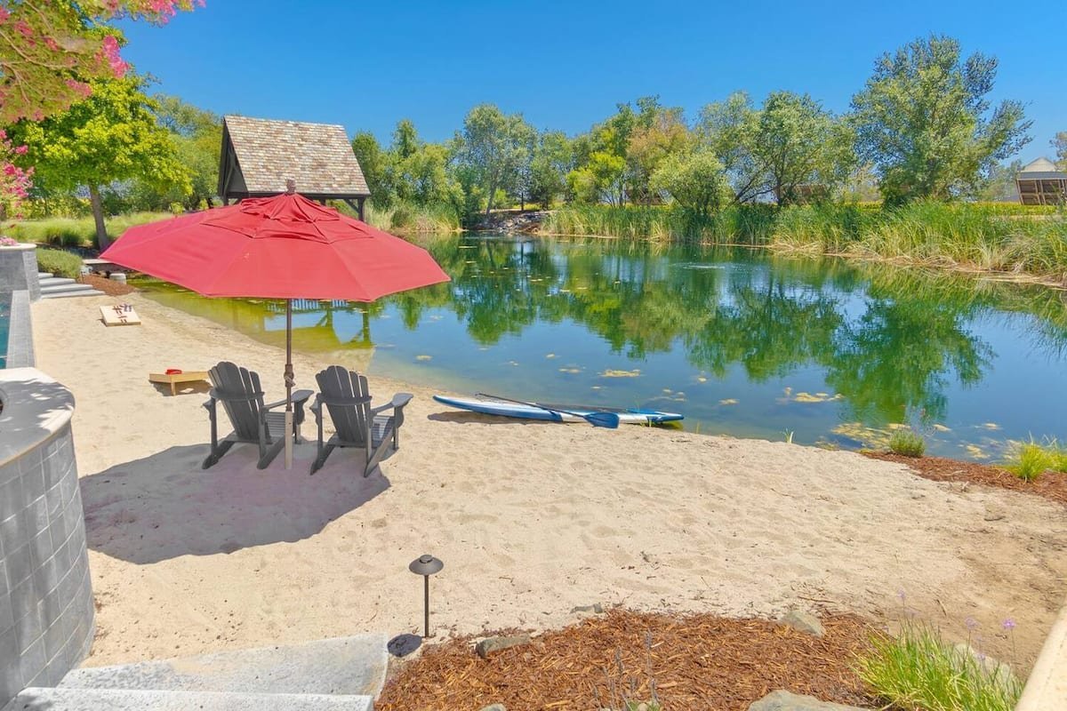 The sandy lake beach with chairs, umbrella and a paddleboard