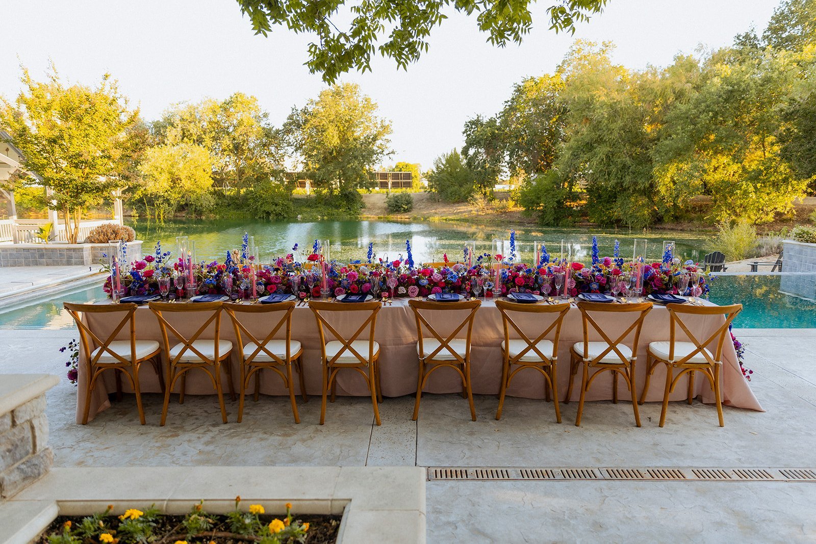A long table set with flowers on the pool terrace, the lake beyond